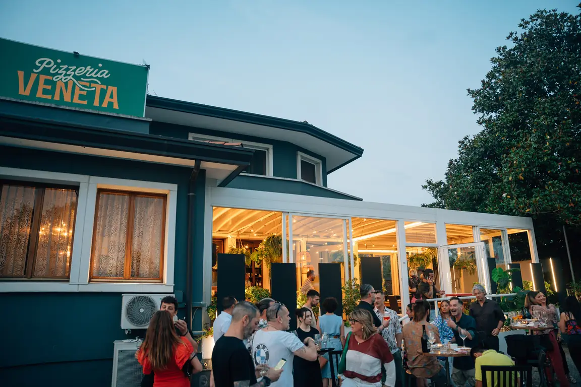 La Pizzeria Veneta di sera, con l'insegna e la veranda illuminata
