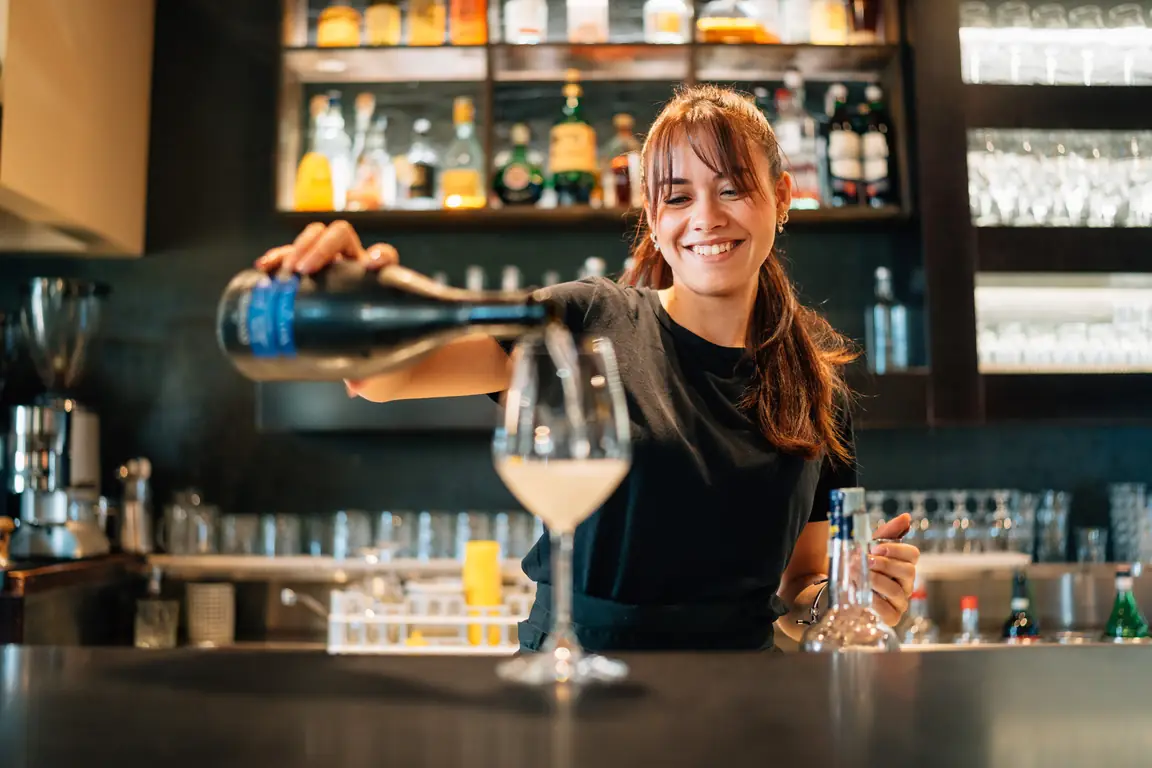 La ragazza del banco versa uno spritz in un calice
