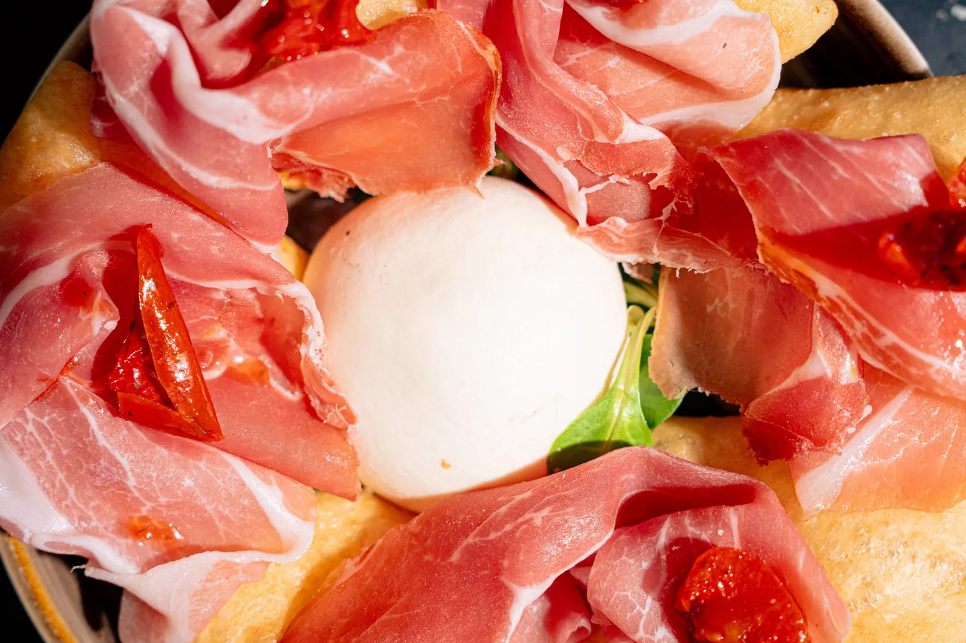 Dettaglio di una pizza con prosciutto crudo e burrata