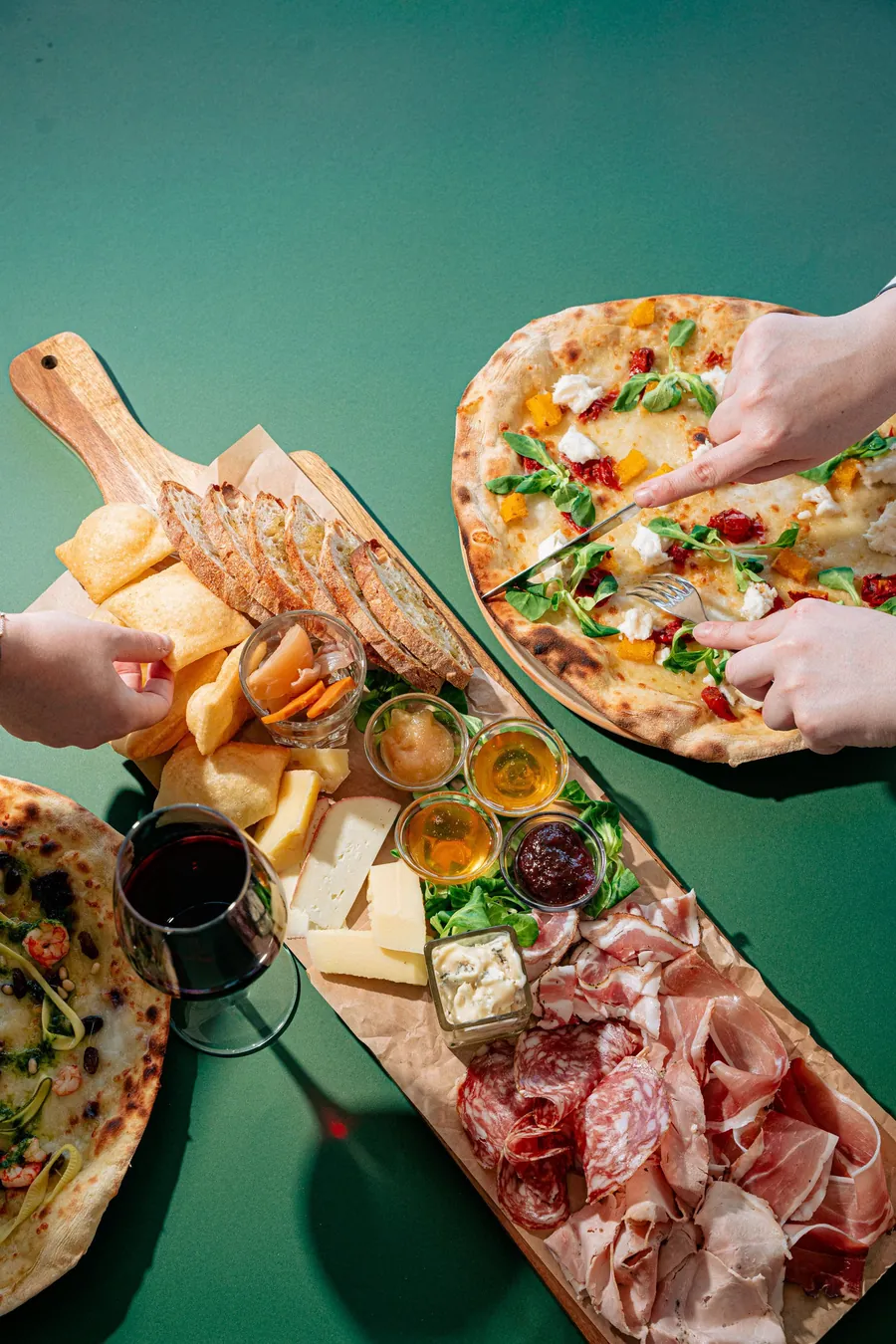 Pizza e tagliere di salumi e formaggi su fondo verde