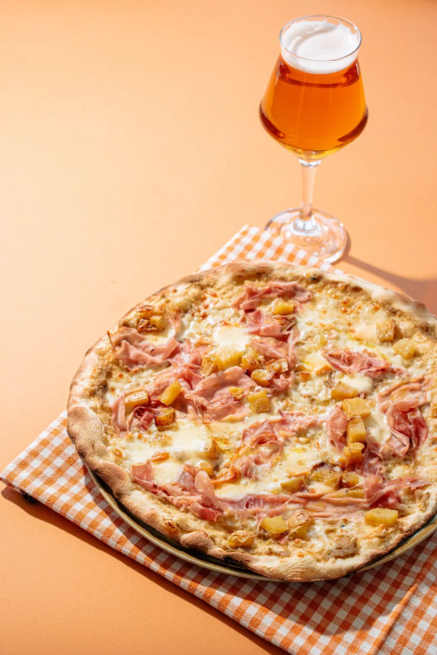 Pizza su tovaglia a quadretti e fondo arancio
