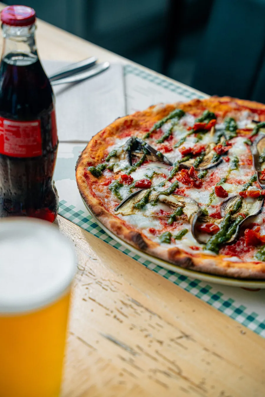 Pizza con crudo e rucola accanto a un bicchiere di birra