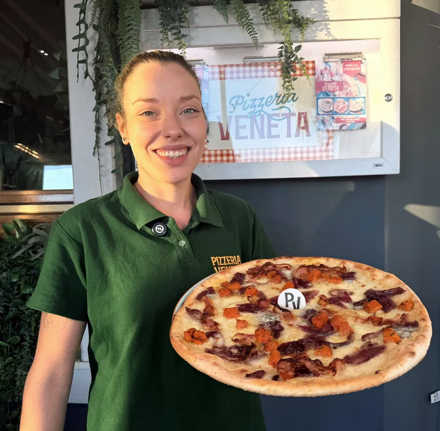Rachele con la divisa della Pizzeria Veneta, un bicchiere di birra e una pizza