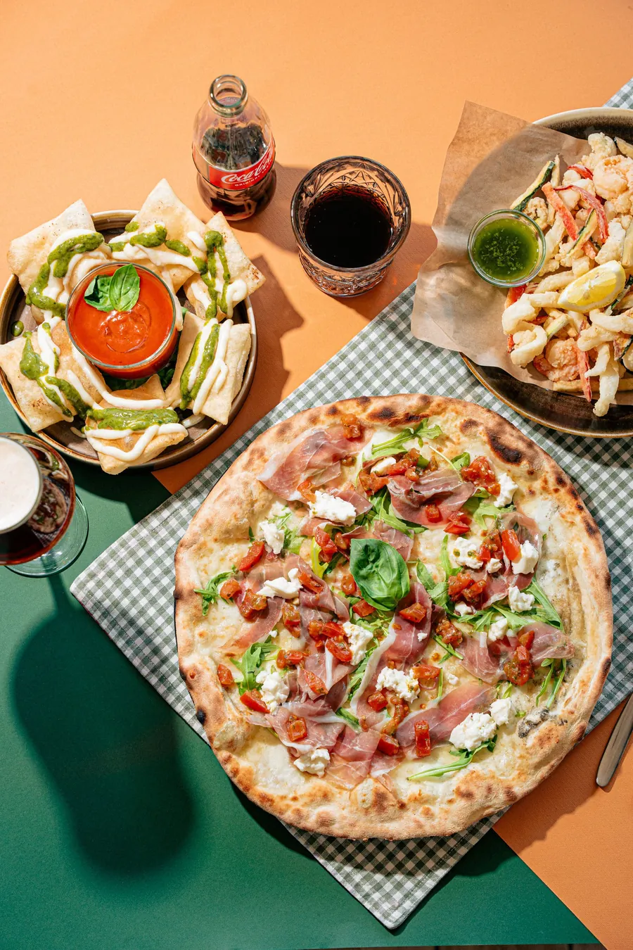 Tavola con pizza, fritti e bibite da dividere in compagnia